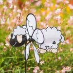 Girouette en forme de mouton planté dans un jardin.